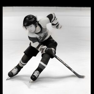 A cute young hockey player skating in an arena during a hockey game